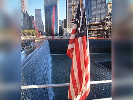 The World Trade Center memorial with an American flag in front.