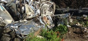 Bales of scrap metal stainliess steel stacked near wildflowers